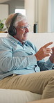 Listening, headphones and old man on sofa for music, wellness and happy mood at home. Relax, song and senior person with smile on couch for audio subscription, streaming or playlist on weekend