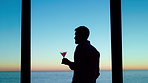 Silhouette, thinking and man with alcohol by window, weekend celebration and me time for reflection. Drink, perspective and calm person with beverage for stress management, view and memory in home