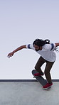 Man, ramp and trick with skateboard for exercise, extreme sports and practice with streetwear. Skateboarder, training and low angle at skatepark for challenge, hobby and balance outdoor with blue sky