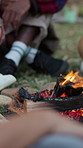 Campfire, outdoor and travel in nature with friends, legs and bonding with group on weekend in woods. Holiday, adventure and warm with fire in forest, feet and hangout with people or social gathering