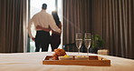 Tray, bed and food in hotel room with couple at window, hug and view with memory, vacation or honeymoon. People, partner and embrace for bonding, love or champagne with wine glass at luxury resort