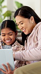 Girl, mother and laugh with tablet on couch for games, bonding or smile with movie choice in family home. Asian people, mom and child with tech, application and happy with online puzzle at house