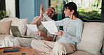 Couple, documents and laptop with high five on sofa for financial success or investment in home. Happy, man and woman with smile or papers on computer for finance, budget planning or winning in house