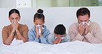 Sick, family and blowing nose with tissue in bed for influenza, virus or infection together in home. Mom, dad and children in blanket with hayfever, sinus or allergies for flu, cold or germs in house