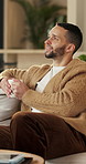 Happy, man and thinking in living room with coffee, morning reflection and relax for weekend break. Person, smile and comfortable with tea cup, thoughts and inspiration for future in home lounge.