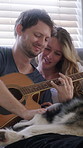Care, happy couple and guitar in home with dog, stroke and bonding together on weekend break. Pet, man and woman with acoustic instrument to play music, love and connection with husky in house