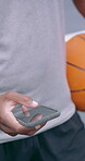 Phone, basketball and typing with hands of man on court for sports league app, communication and fitness tracking. Text message, social media and game scores check with person and mobile outdoor