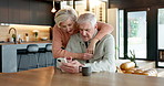 Hug, phone and senior couple in home with social media, texting or chatting together on weekend Coffee, happy and elderly woman embracing woman on cellphone for reading blog on mobile app in house.