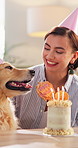 Excited, woman and dog in home with birthday cake, blow candles and cheering for adoption milestone. Pet owner, happy and golden retriever in lounge for celebration, bonding and treat at party