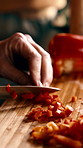 Person, knife and hands with cut peppers on chopping board for healthy meal prep in kitchen. Chef, culinary artist or slicing natural organic ingredients for cooking recipe, diet or vegan cuisine