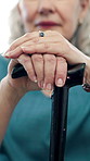 Hands, cane and senior woman for retirement, support or mobility aid and relax in home. Closeup, elderly person with a disability and walking stick for help, assistance and balance or arthritis