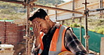 Construction site, man and headache with stress for building, renovation and civil engineering mistake. Tired contractor, burnout and crisis with industrial issue, architecture or maintenance