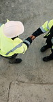 People, architect or meeting with handshake on construction site for building partnership above. Top view, contractor or civil engineer shaking hands with helmet or hard hat for b2b architecture deal