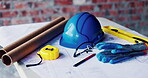 Construction, helmet and blueprint with gear on table, infrastructure schematic or safety equipment. Building plan, scale or ppe for renovation project, tape measure or tools for property development
