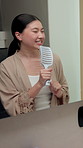 Woman, singing and mirror in bathroom with hairbrush, morning routine and good mood for wellness. Happy, Asian person and music karaoke in house with hair tools, reflection and getting ready for day.