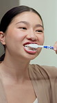 Home, brushing teeth and Asian woman in mirror for dental hygiene, gum disease and oral care. Reflection, morning and person with toothbrush for wellness, cleaning and fresh breath in bathroom