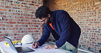Writing, review and man with blueprint at construction site, planning update and change for renovation. Engineering, remodeling or architect with revision of schematic, laptop or property development