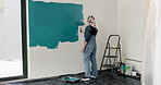 Woman, roller and painting in home with renovation project, interior design and property makeover. Back, creative person and art tools in living room with house improvement, diy or remodeling process