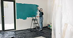 Woman, roller and painting in house with interior design, renovation project and property makeover. Back, creative person and art tools in living room for home improvement, diy or remodeling process.