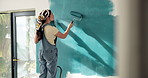 Woman, roller and painting in house with renovation project, interior design and property makeover. Back, creative person and art tools in living room with home improvement, diy or remodeling process