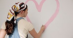 Woman, heart or interior design with paint on wall for nursery, love or fun activity for home decor. Female person, painter or shape with romantic gesture or symbol for mural art or style in house