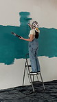 Woman, happy and painting wall with brush, ladder and hobby for self expression. Process, interior design and home decor with diy project, paint for renovation and artist with balance and creativity