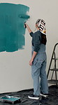 Woman, back and painting wall with brush for creativity, self expression and therapeutic hobby. Remodelling, personalisation and home decor with diy project, interior design and paint for renovation