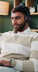 Headphones, laptop and typing with man on sofa in home for planning, remote work or research. Agenda, computer and streaming with happy person in apartment for feedback or report as freelancer