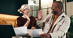 Documents, high five and laptop with interracial couple on sofa in home living room for finance. Computer, paperwork and success with mature people hug in apartment for financial discussion or review