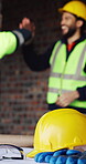 Helmet, architecture and ppe on table for safety, construction site or building design. Floor plan, people high five and hardhat for engineering, equipment and tools for infrastructure development 