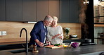 Couple, reading and phone in home for cooking, recipe and online tutorial for healthy food. Mature people, feeding and laugh at house with mobile, instructions and meal prep with vegetables for lunch