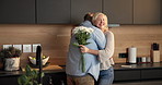 Love, flowers and old couple in home for hug, support or bonding together in kitchen. Smile, commitment and elderly man with woman for gift with marriage, anniversary and bouquet in apartment