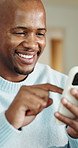 Phone, scrolling and hands of black man in home with texting, chatting or social media on mobile app. Technology, laugh and male person with cellphone for funny meme online on website in apartment.