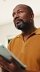 Remote work, thinking and man in home on tablet for internet, networking and website for research. Mature, low angle and African person with tech for online report, proposal and freelance project