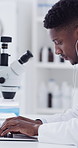 Black man, scientist and typing in lab with laptop, research and medical results of experiment. Person, earphones and microscope and tech with liquid sample, specimen analysis and vaccine development