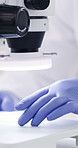 Hands, scientist and petri dish in lab with microscope, research and medical study for experiment. Person, inspection and biotechnology with liquid sample, specimen analysis and vaccine development