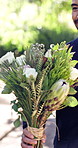Flowers, giving and wedding with couple outdoor in park together for celebration or milestone. Bride, groom and smelling with people in nature for commitment event, marriage tradition or relationship
