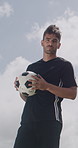 Soccer, catch and face of man with ball outdoor for playing game, training and practice for match. Serious, athlete and portrait of person with blue sky for exercise, challenge and fitness for club