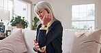 Senior, woman and elbow pain in home with discomfort, nerve compression and osteoarthritis. Retirement, pensioner and joint inflammation in living room with tendon ache, muscle tension and massage