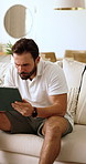 Reading, tablet and man on sofa in home with relax for blog on saving, investment or finance tips. Happy, technology and male person in living room for website on financial growth with advice app.