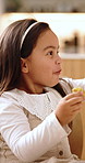 Eating, happy and child in home for lunch, snack or meal with nutrition on weekend in dining room. Smile, growth and girl kid enjoying samosa for craving or food with development in apartment.