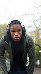 Fitness, tired and black man with headphones, outdoor and exercise with fatigue, breathing and sweating. Challenge, African person or athlete with wellness, exhausted and burnout with rest or workout