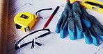 Gloves, architecture and blueprint on table with safety documents, construction or building design. Floor plan, paperwork and glasses for ppe, equipment and tools for infrastructure development
