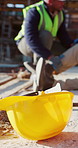 Helmet, people and injury on construction site with accident, civil engineering error and safety issue. Engineer, team and hurt leg outdoor with PPE, coworker assistance or man with medical emergency