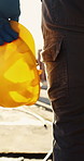 Hand, engineer and walk with helmet at construction site for safety or infrastructure development. Architect, hard hat or legs of person outdoor with protection gear, flare or engineering compliance