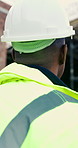 Back, thinking and man with helmet at building site, safety compliance and property development idea. Outdoor, construction project and architect with vision of renovation, hard hat and planning