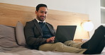 Businessman, relax and bedroom with laptop in hotel for remote work, schedule or communication. Man, freelancer or smile with computer in bed for online network, internet or connection in apartment