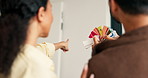 Back, couple and talking at new house with swatches, paint sample and ideas for interior design. People, pointing and planning in lounge with color palette, renovation and diy makeover for remodeling