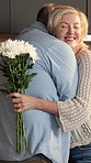 Flowers, hug and senior couple in kitchen for surprise, celebration and gift for love in home. Marriage, happy and man and woman with bouquet, smile and embrace for affection, trust and connection