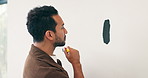 Brush, painting and thinking with man in house for diy project or renovation decision. Choice, color and considering with serious person in apartment for home improvement, makeover or upgrade